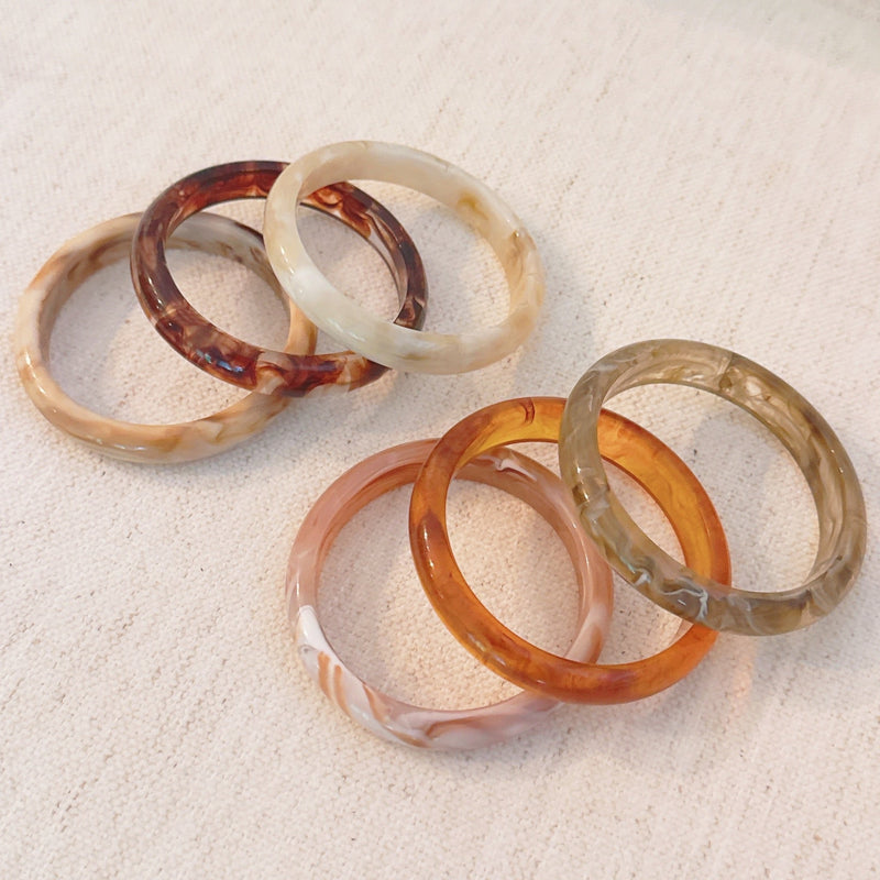 Set of three bold resin bangles in natural earth tones, featuring a mix of marbled and solid finishes for a stylish stacked look.