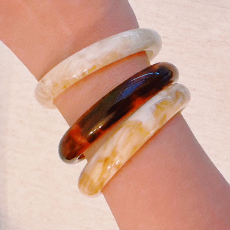 Set of three bold resin bangles in natural earth tones, featuring a mix of marbled and solid finishes for a stylish stacked look.