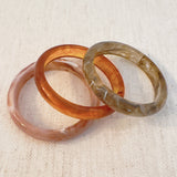 Set of three bold resin bangles in natural earth tones, featuring a mix of marbled and solid finishes for a stylish stacked look.