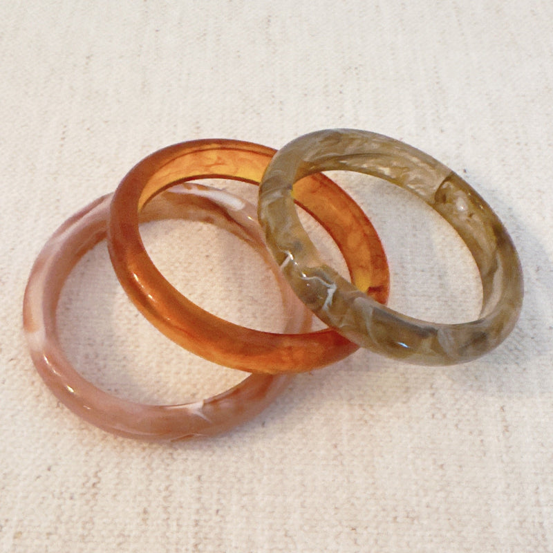 Set of three bold resin bangles in natural earth tones, featuring a mix of marbled and solid finishes for a stylish stacked look.