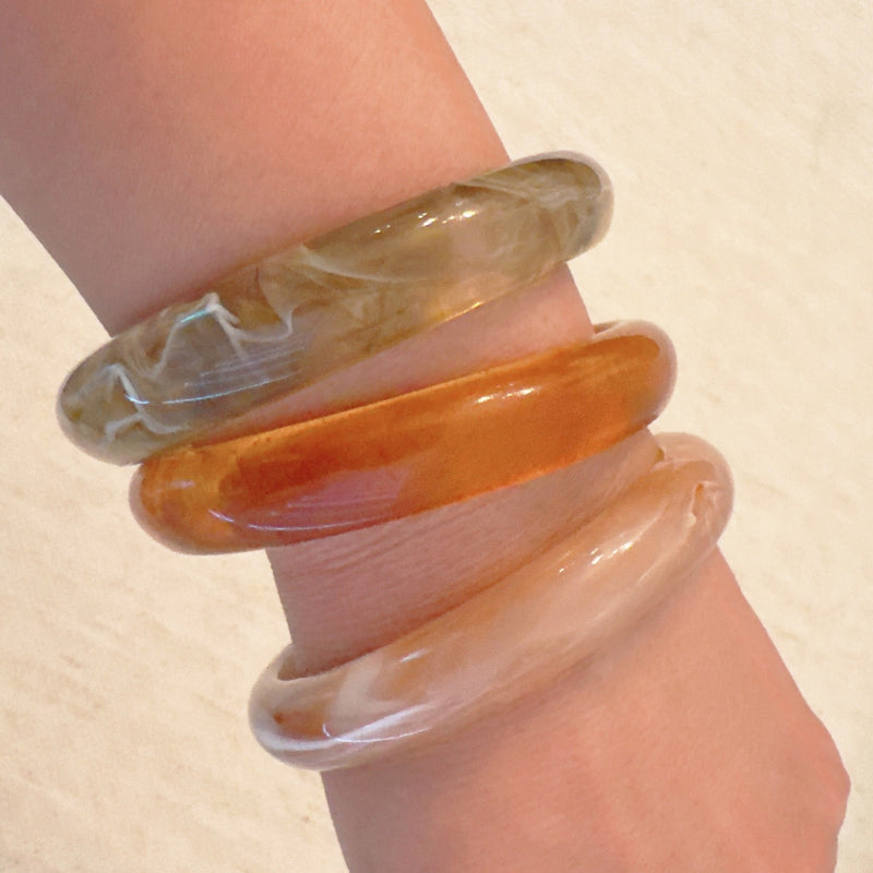 Set of three bold resin bangles in natural earth tones, featuring a mix of marbled and solid finishes for a stylish stacked look.
