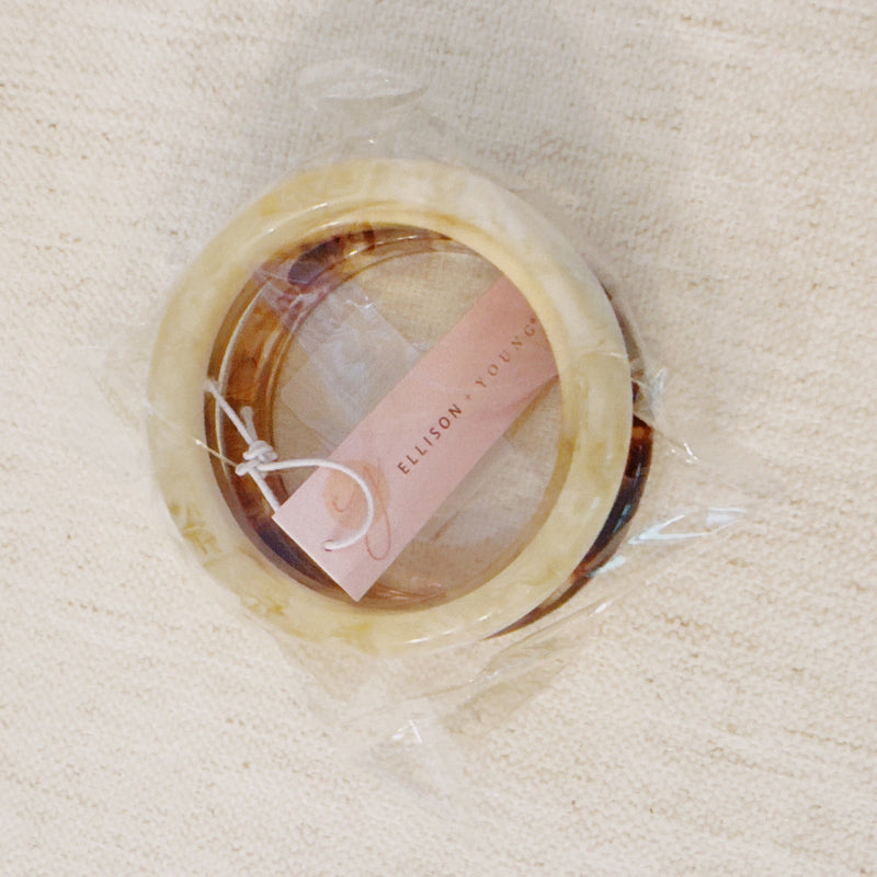 Set of three bold resin bangles in natural earth tones, featuring a mix of marbled and solid finishes for a stylish stacked look.