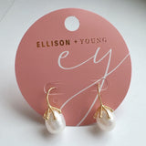 A pair of elegant drop earrings featuring organic-shaped baroque pearls with gold-tone vine-like prong detailing, suspended from sleek curved gold hooks, displayed against a dark textured background.