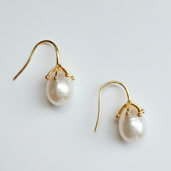 Pearl earrings with gold hooks on a light gray background