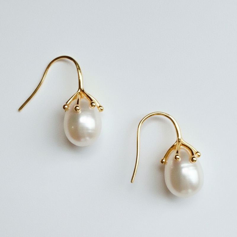 Pearl earrings with gold hooks on a light gray background