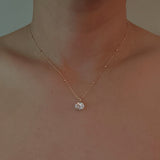 Gold-tone necklace featuring an oval-cut pendant with a sparkling crystal center, offering a refined and elegant touch.