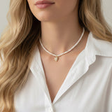 Refined pearl necklace featuring a small gold heart pendant adorned with sparkling crystals. The minimalist yet elegant design offers a timeless touch perfect for layering or wearing on its own.