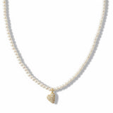 Refined pearl necklace featuring a small gold heart pendant adorned with sparkling crystals. The minimalist yet elegant design offers a timeless touch perfect for layering or wearing on its own.