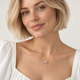 Model wearing the Ellison + Young Pear Cut Crystals Pendant Necklace, two pear-cut cubic zirconia stones on a dainty gold chain with a white square-neck top