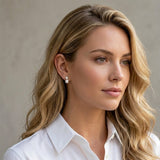 a woman wearing Gold stud earrings featuring round clear crystal accents paired with glossy white pearl drop details in a classic and elegant design