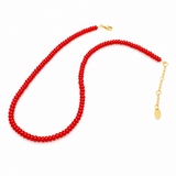 Close-up of a bold red beaded necklace featuring uniformly round, glossy beads strung together in a classic strand, creating a vibrant and timeless accessory.