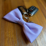 Purple bow tie on a wooden surface with a keychain in the background