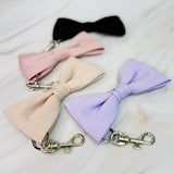 Four colorful bow ties with keychains on a light marble surface