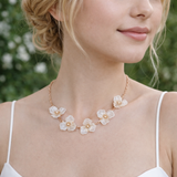 Woman wearing a floral necklace with a blurred green background