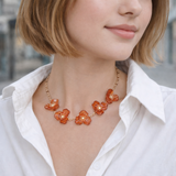 Woman wearing a floral necklace with orange flowers and gold chain.