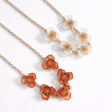Gold chain necklace featuring multiple floral-shaped charms with detailed centers, available in light and dark color variations, designed as a bold statement piece.