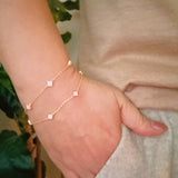 Delicate layered chain bracelet featuring a petite clover charm centerpiece, offering a minimalist and feminine touch with a refined gold-tone finish.