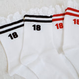 Set of two sporty crew socks featuring playful preppy details like ribbed texture and delicate lace trim at the cuff, blending athletic comfort with feminine charm.