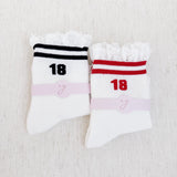 Set of two sporty crew socks featuring playful preppy details like ribbed texture and delicate lace trim at the cuff, blending athletic comfort with feminine charm.