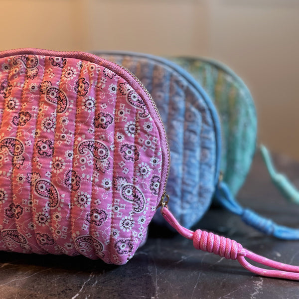 Quilted cosmetic case featuring a colorful paisley pattern and zip closure, combining stylish design with soft, padded texture for everyday beauty storage.