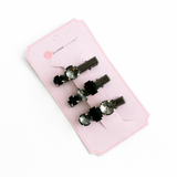 Set of four black hair clips with green rhinestones on a pink card with 'Ellison & Union' branding.
