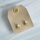 Elegant stud earrings featuring a brilliant clear crystal paired with a small luminous pearl in a gold-tone setting. The dual-stone design combines modern sophistication with timeless charm, perfect for everyday wear or special occasions.