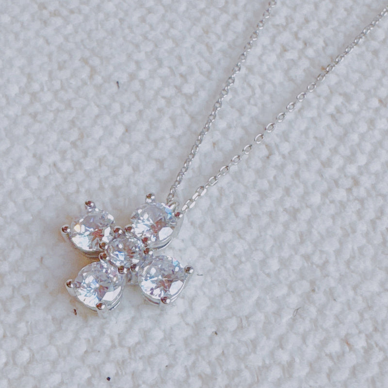 Silver cross pendant necklace featuring a symmetrical arrangement of radiant-cut cubic zirconia stones, creating a brilliant and elegant sparkle on a fine silver chain.