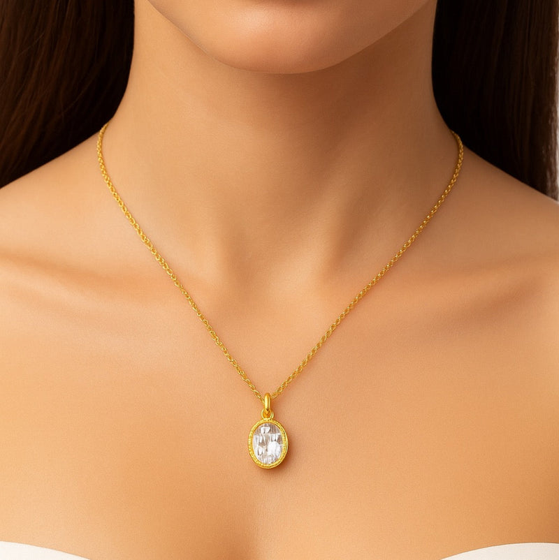 Close-up of a woman wearing a delicate gold chain necklace featuring a vintage-style oval pendant with a radiant engraved pattern and sparkling center stone, resting elegantly on her collarbone.