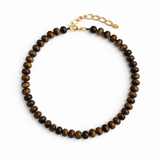 A collection of polished gemstone bead necklaces in various colors, including deep blue, green, brown, pink, and cream. Each necklace features smooth, rounded beads with a glossy finish, offering a timeless and versatile accessory look.