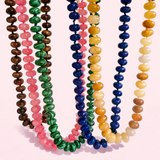 Colorful beaded necklaces on a light pink background