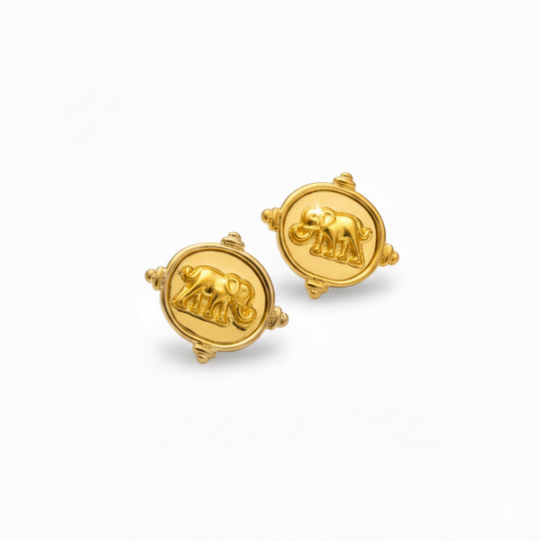 Close-up of a pair of round gold-tone stud earrings featuring a raised elephant motif on a medallion-style base with detailed edge accents.
