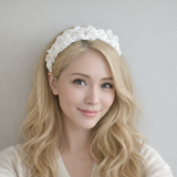 Wide padded headband featuring layered white fabric flowers with clustered pearl centers, arranged in a romantic, textured design for a feminine and elegant hair accessory.