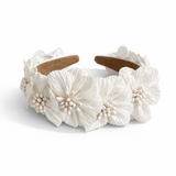 Wide padded headband featuring layered white fabric flowers with clustered pearl centers, arranged in a romantic, textured design for a feminine and elegant hair accessory.