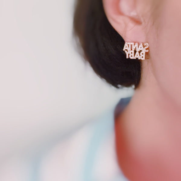 Festive stud earrings with gold-tone holiday charm and subtle sparkle – chic Santa baby style