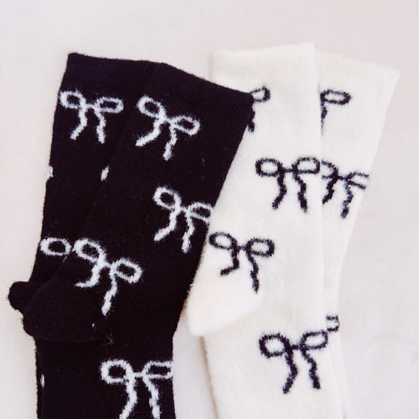  Set of two fuzzy socks featuring playful bow accents, combining cozy comfort with a touch of sassy, feminine charm.