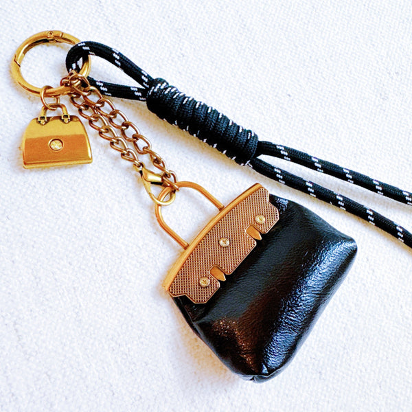 Glamorous bag charm featuring a mini purse design with gold-tone accents and playful details—perfect for adding a touch of sass and luxe to any handbag or tote.