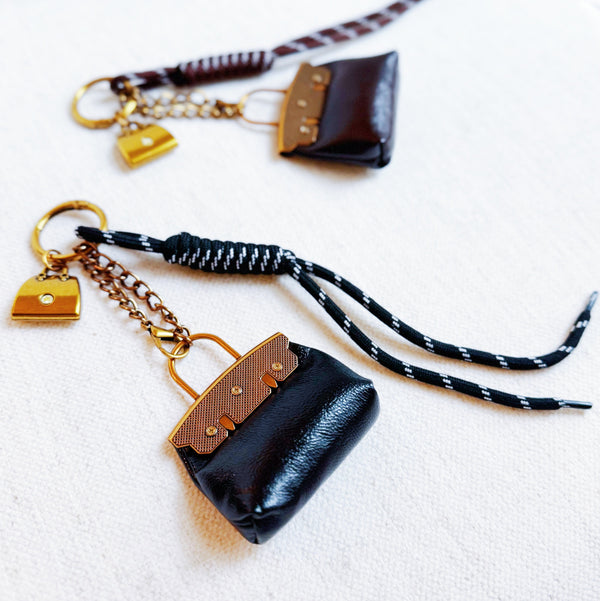Glamorous bag charm featuring a mini purse design with gold-tone accents and playful details—perfect for adding a touch of sass and luxe to any handbag or tote.