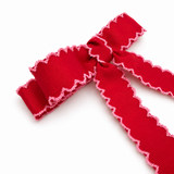 Red ribbon with scalloped edge on a white background