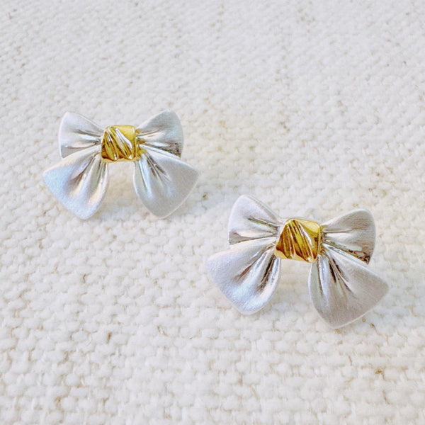 Charming white bow-shaped stud earrings with a gold center wrap—offering a sweet, feminine look perfect for both casual and dressy outfits.