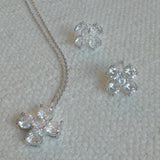 Silver-tone stud earrings in a floral clover shape, each featuring four pear-shaped cubic zirconia stones arranged in a symmetrical pattern for a radiant and delicate sparkle.