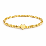 Gold beaded bracelet with a heart charm on a white background