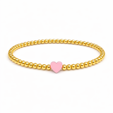 Gold beaded bracelet with a pink heart charm on a white background