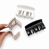 Three hair clips (white, beige, black) on a white background