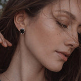 A pair of black gemstone stud earrings featuring faceted rectangular stones set in silver-toned prong settings, offering a bold and refined statement look.