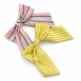 Striped ribbon bow hair clips in pastel pink with green stripes and soft yellow with blue stripes. The Striped Ribbon Bow Hair Clip – Classic Preppy Style adds a charming, polished accent to any hairstyle, blending playful color with timeless sophistication.