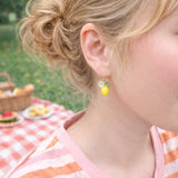 Close-up of a child wearing earrings with a picnic setting in the background