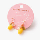 Yellow lemon-shaped earrings on a pink Ellison + Young card.
