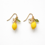 Drop earrings featuring bright yellow lemon charms with green leaf accents and gold-tone hooks, designed for a playful, summer-inspired look.