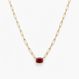 Gold chain necklace with a red gemstone on a white background