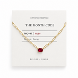 Gold necklace with a red gemstone on a white card displaying 'The Month Code' branding.